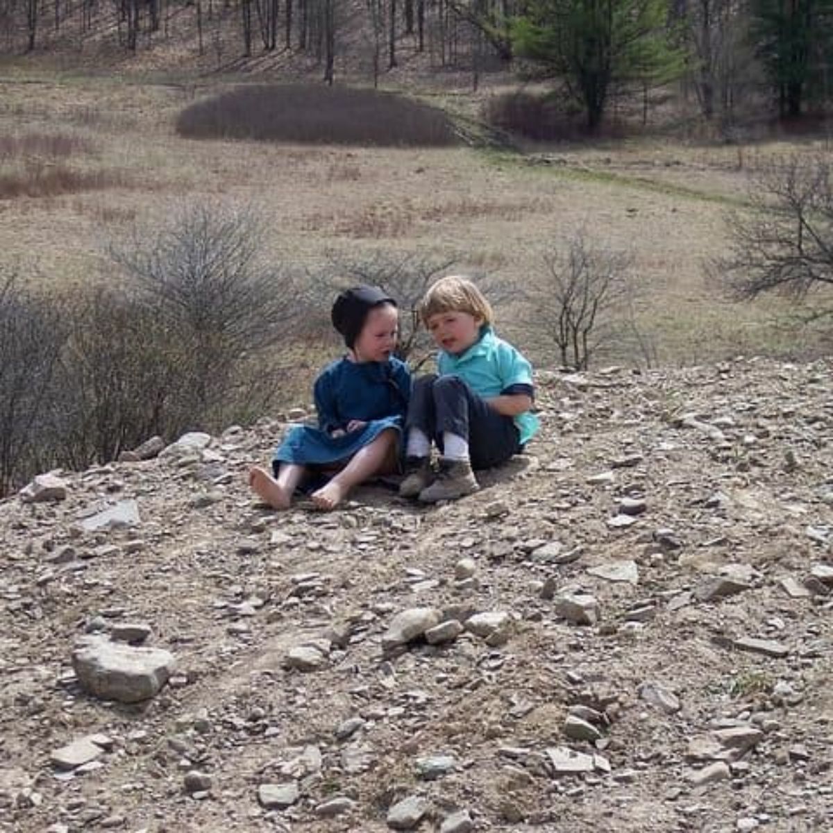Amish kids sitting in the dirt.