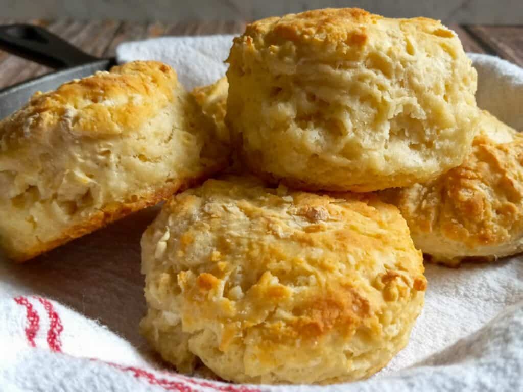 tall, fluffy homemade biscuits piled into a skillet.