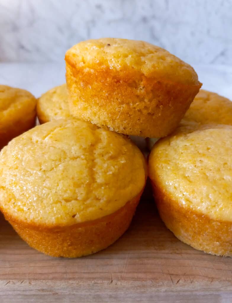 cornbread muffins stacked on a board.