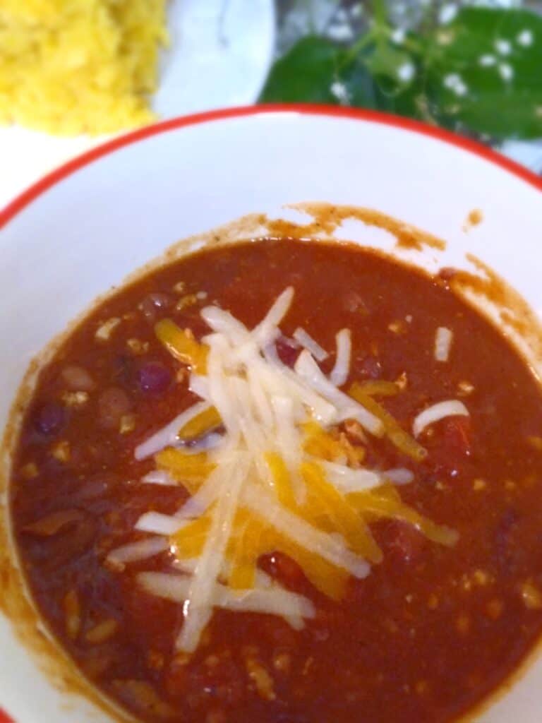 Amish chili soup in a bowl with shredded cheese on top.