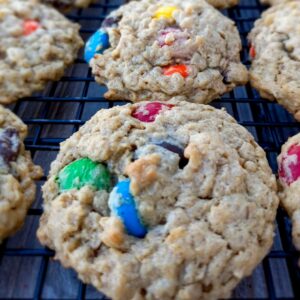 monster cookies with M&Ms on a wire rack.