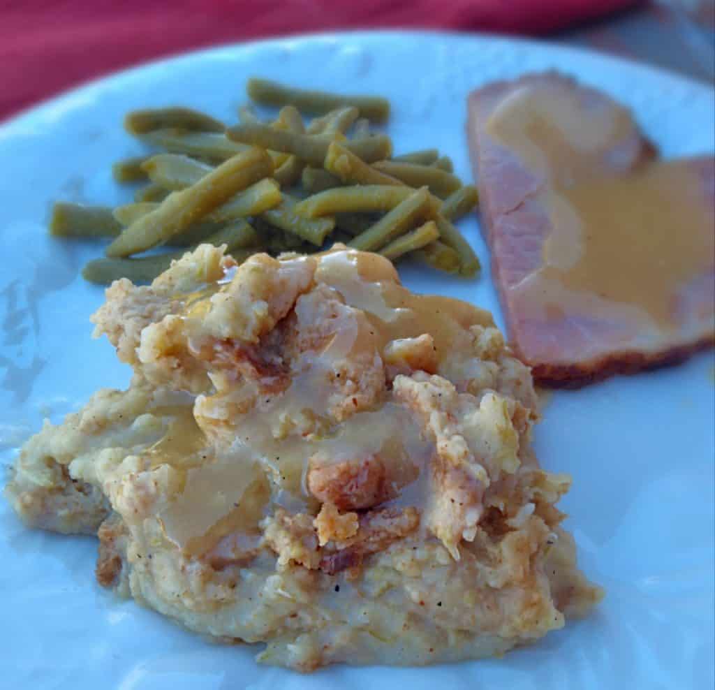 a plate with Pennsylvania potato filling,ham,and green beans