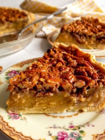 a slice of the best creamy pecan pie with more pie in the background.