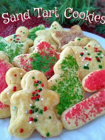 a plate of beautifully sprinkled Christmas sand tart cut-out cookies.