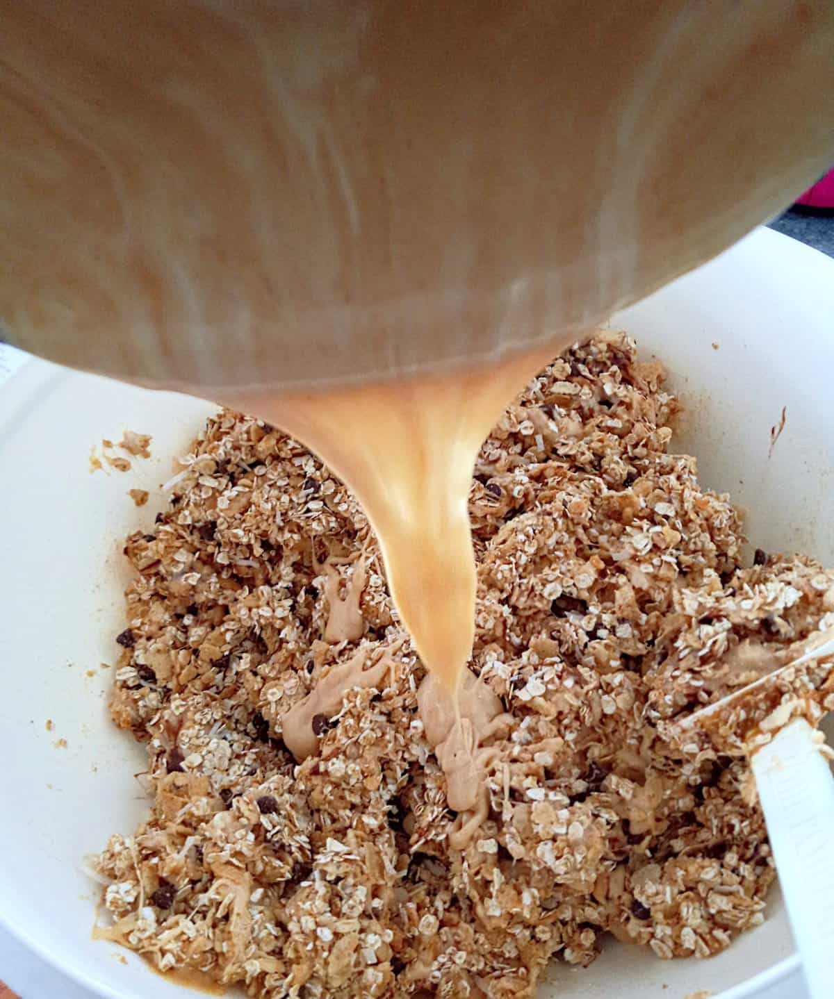 pouring melted marshmallow mixture into granola mixture