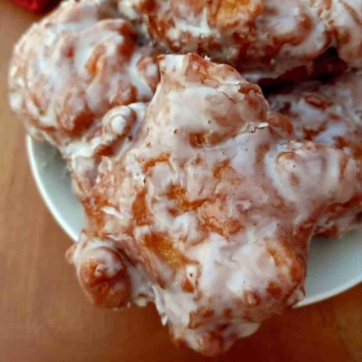 glazed homemade apple fritters on a plate.