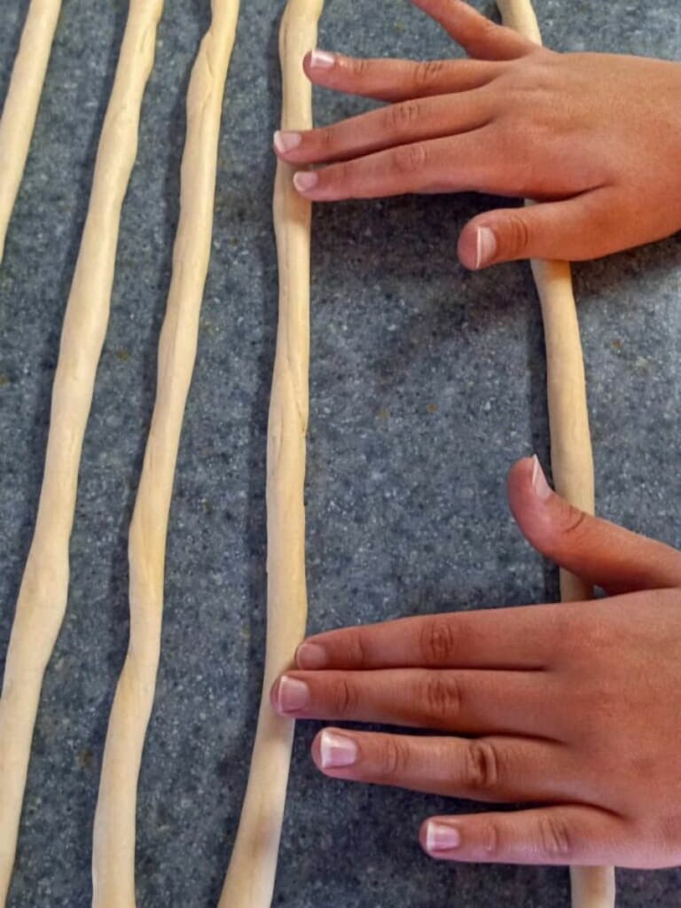 rolling pretzel dough into thin ropes.