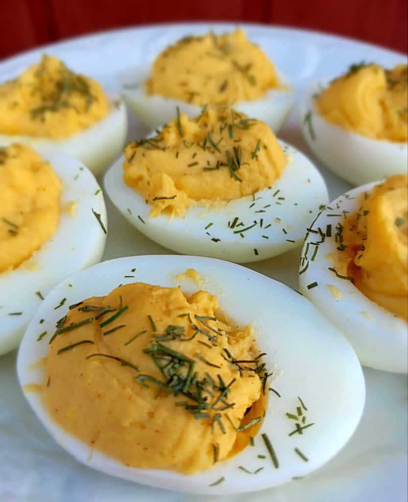Amish deviled eggs sprinkled with chives on a plate.