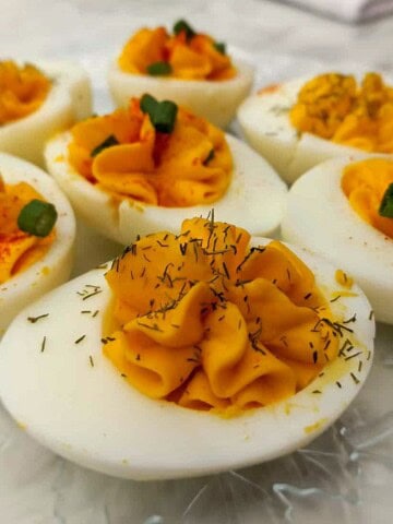 deviled eggs piped with filling on a glass plate.