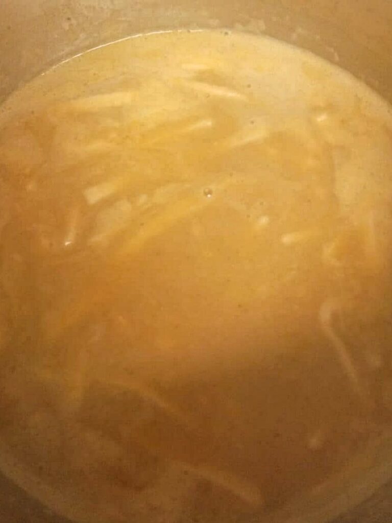 a large pot of browned butter with broth and noodles.