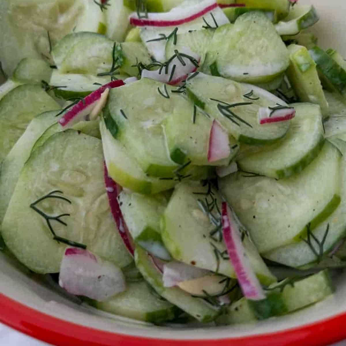 a close-up look at a bowl full of Amish cucumber salad with fresh dill