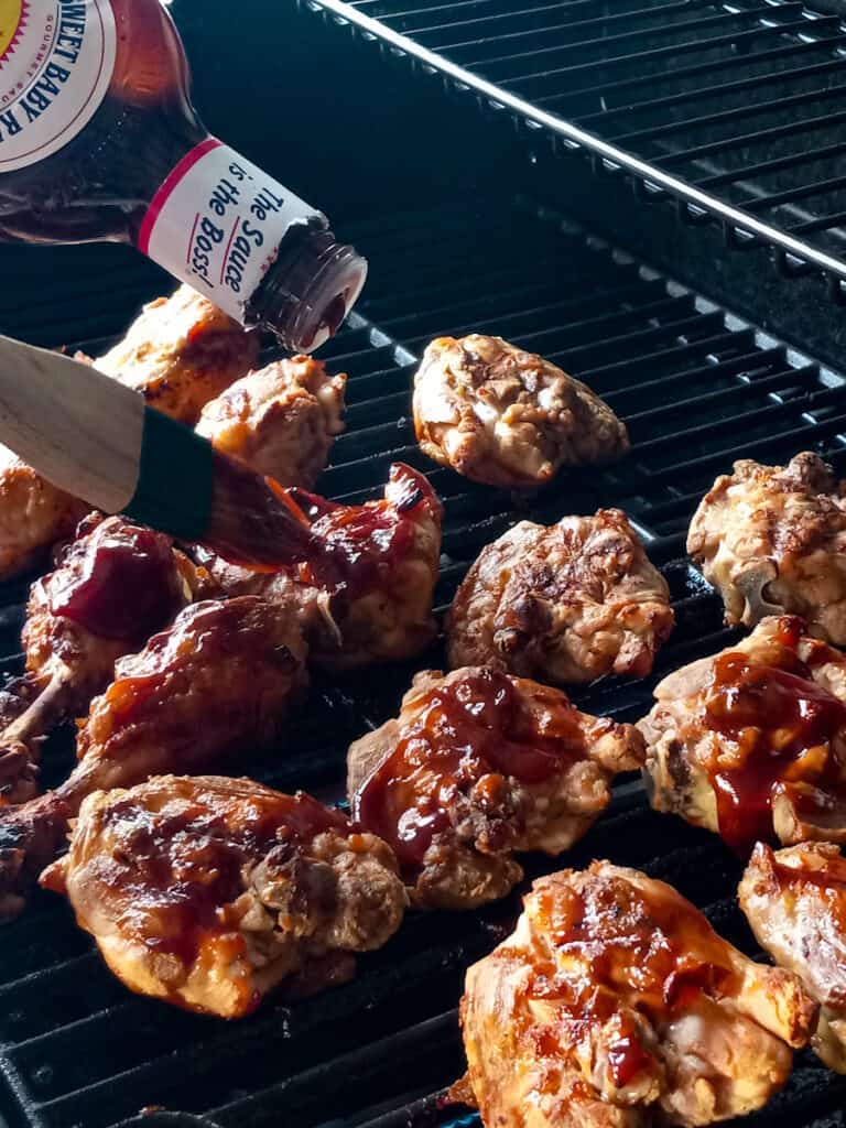 brushing barbecue sauce onto the grilled chicken