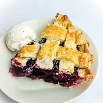 slice of Amish blueberry pie and a scoop of ice cream on a small plate