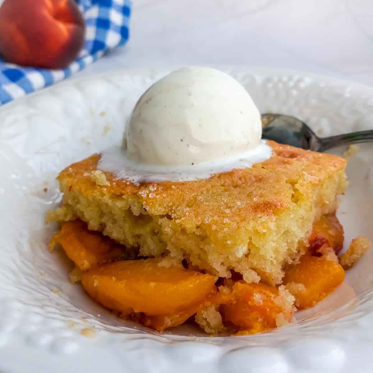 Amish peach cobbler in a dish topped with a scoop of ice cream