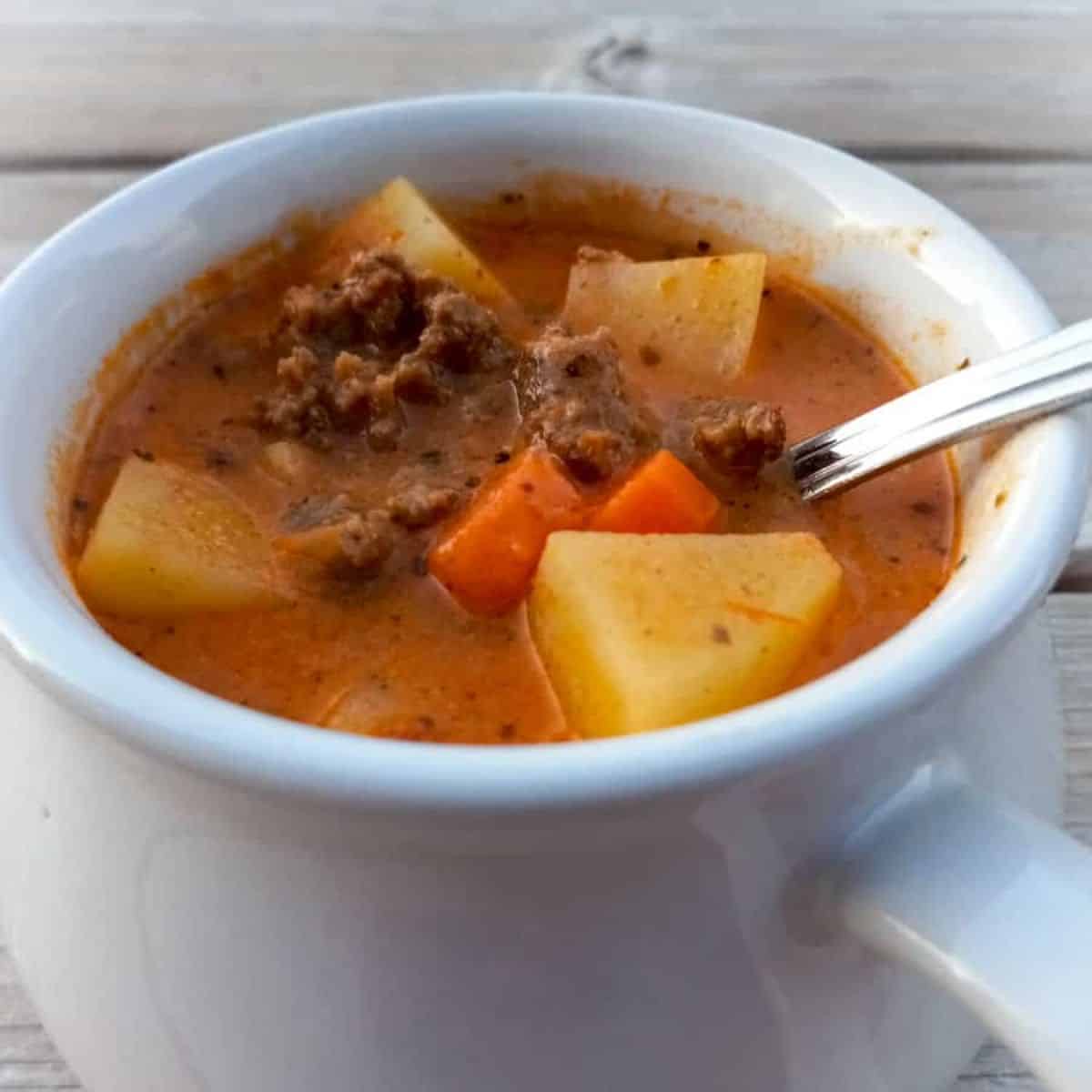 a small crock of hearty hamburger soup with potatoes and carrots.