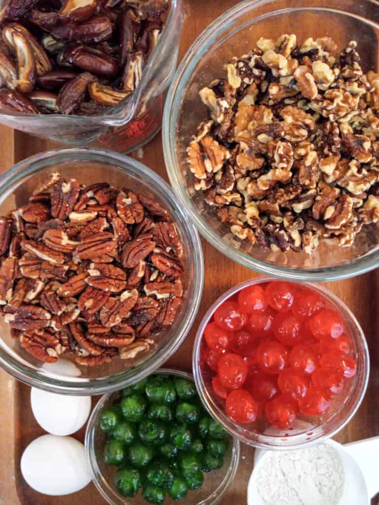 Ingredients for fruitcake- pecans, walnuts, dates, cherries, eggs, and flour