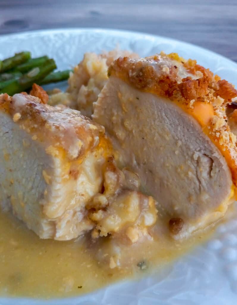 Amish oven-baked creamy chicken breast cut in half on a plate with rice and asparagus
