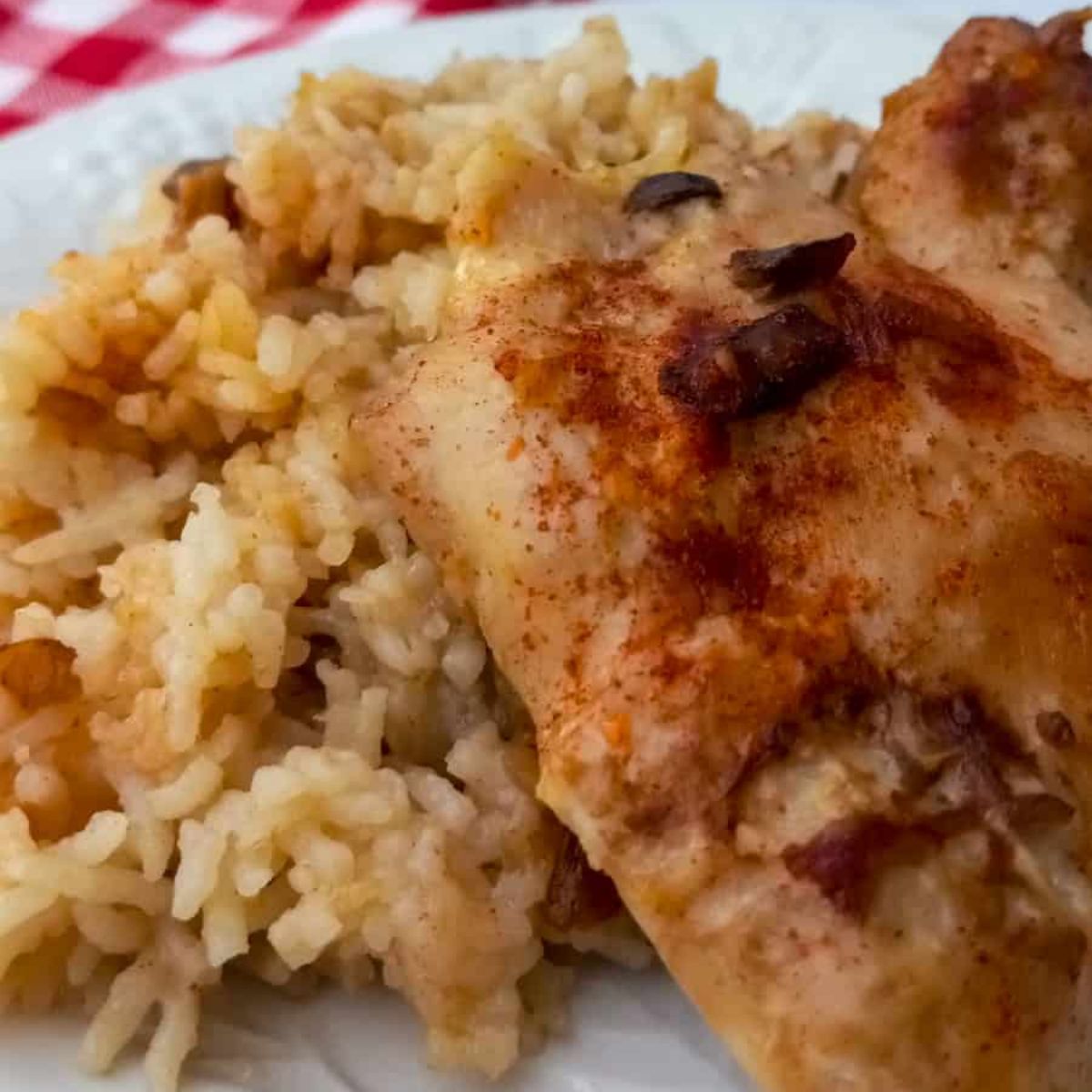 a plate piled with Amish chicken and rice casserole, featuring fluffy rice and a baked chicken thigh.