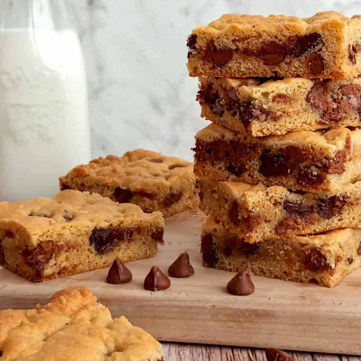 a big stack of homemade choicolate chip bars with a jar of milk.
