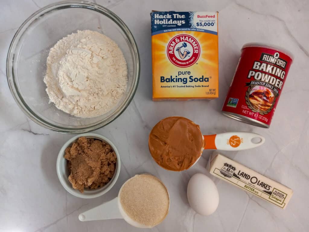 ingredients - flour, baking soda, baking powder, brown sugar, peanut butter, sugar, butter, and egg