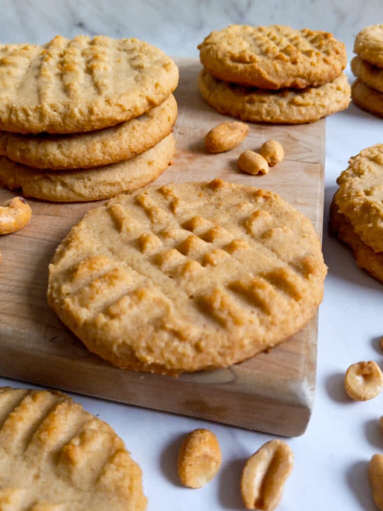 Amish peanut butter cookies on a board and scattered around with peanuts