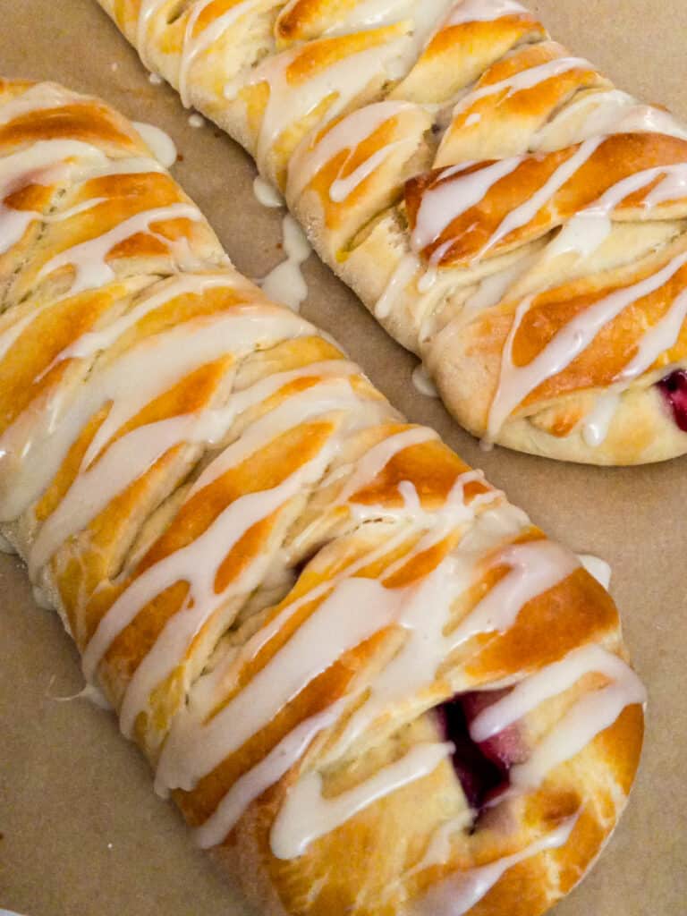 two fruit-filled Danish pastry braids with glaze drizzled over the top