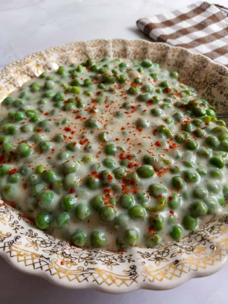 bowl of peas in cream sauce with paprika sprinkled on top