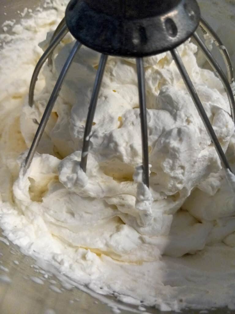 whipped cream in a bowl with whisk