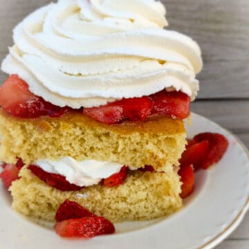 shortcake piled with strawberries and whipped cream on a plate
