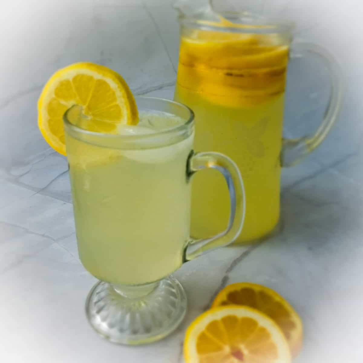 small pitcher of Amish lemonade and a cup full of lemonade with a lemon slice