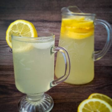 small pitcher and a cup of lemonade with lemon slices