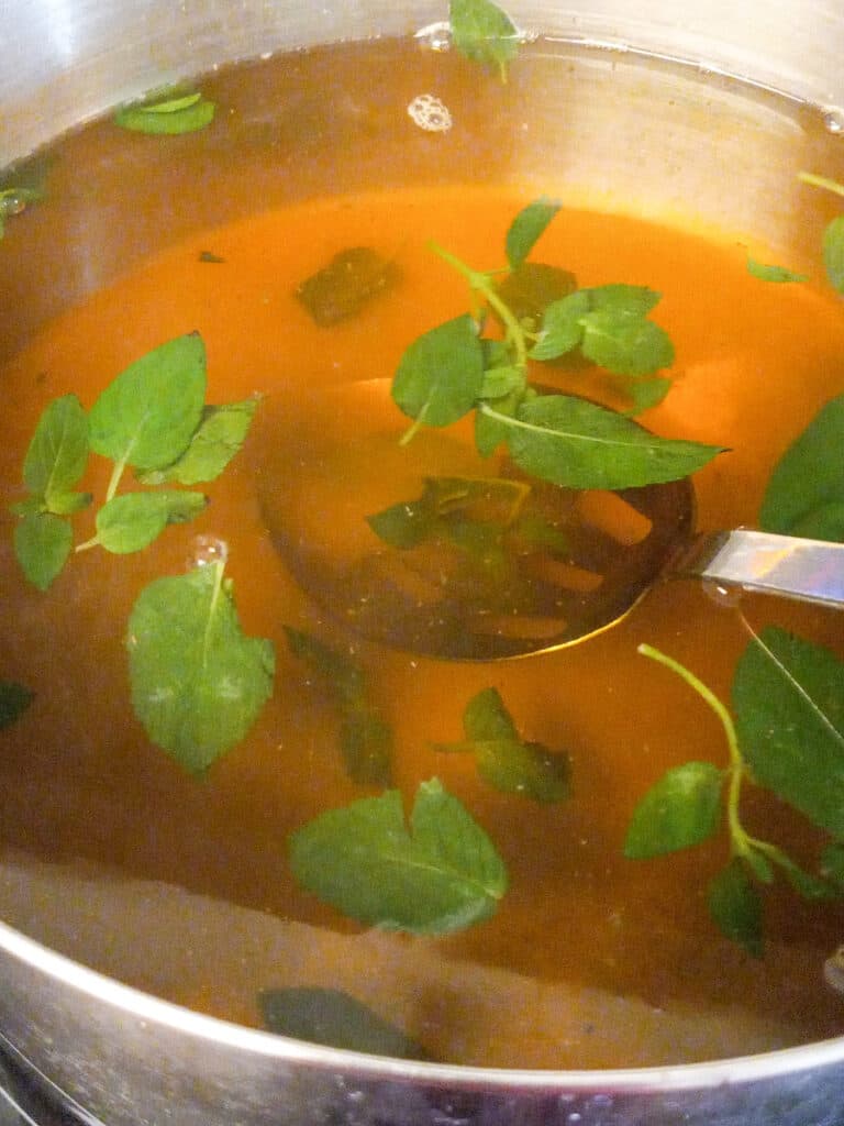 brewed tea in a pot with a few mint leaves floating on top