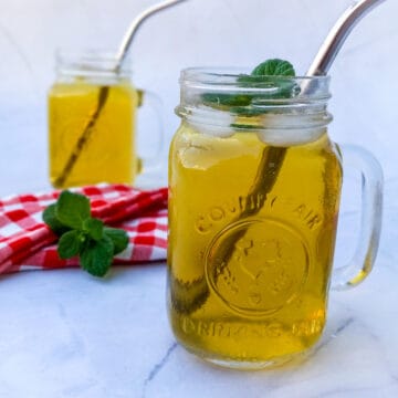 two cups of tea with metal straws and mint leaves