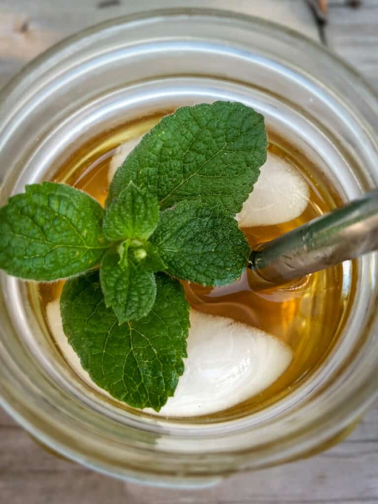 cup of meadow tea with ice and mint leaves on top