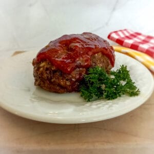 an Amish mini cheesy meatloaf on a plate with parsley for decor