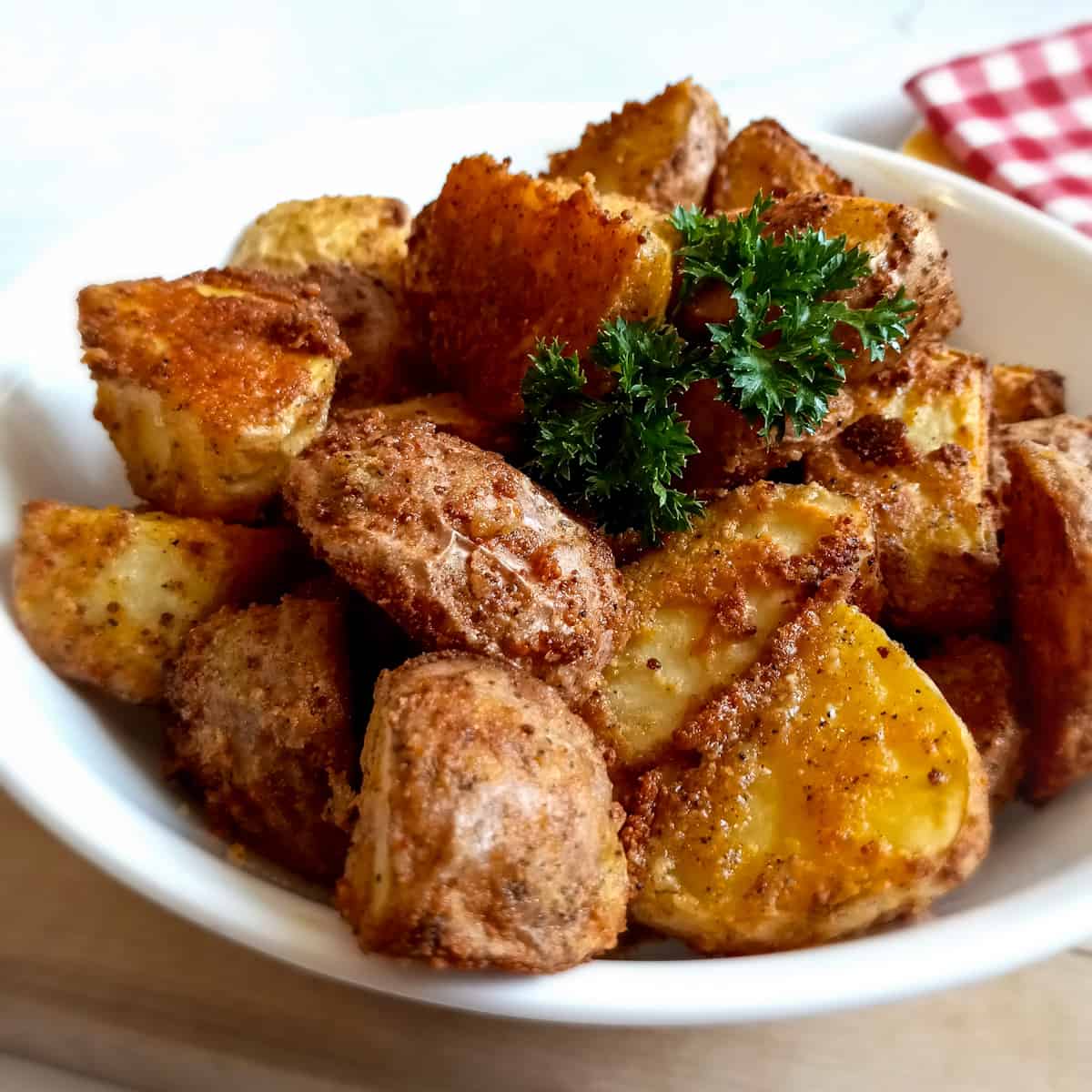 Crispy Parmesan Potatoes in a serving bowl topped with fresh parsley