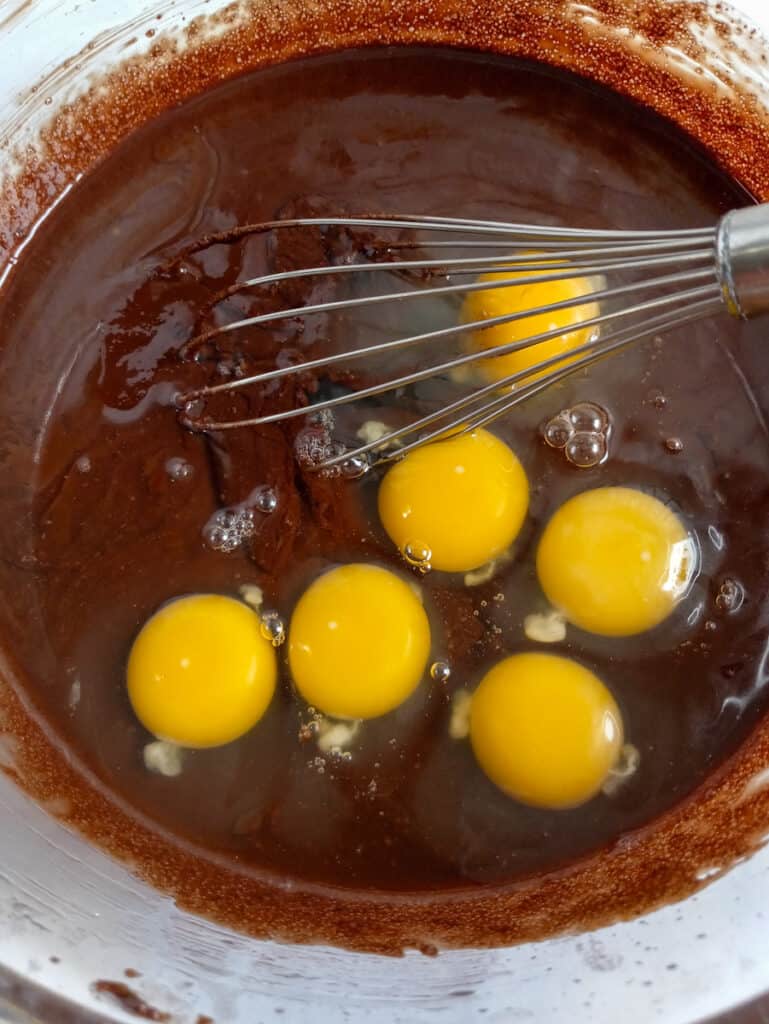 melted chocolate, butter, and sugar in a bowl with eggs on top
