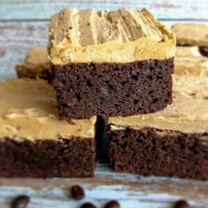 coffee brownies with frosting and coffee beans scattered around