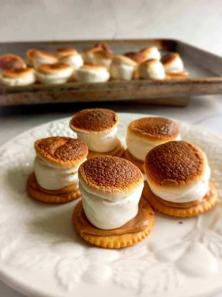 broiled marshmallow hats on a plate and some on a baking tray.
