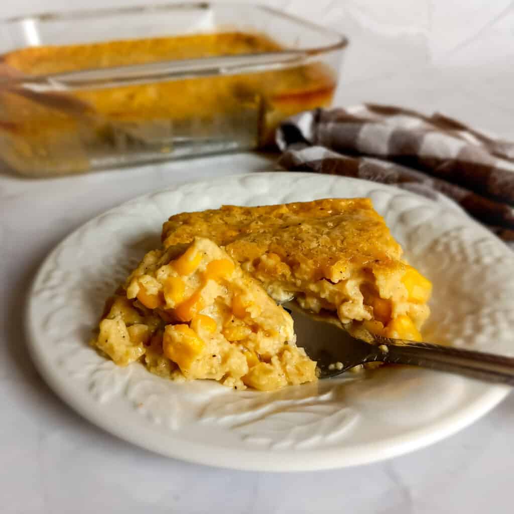 Amish baked corn on a plate and a dish of corn casserole in a pan