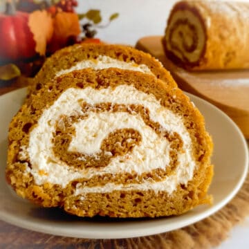 slices of pumpkin roll on a plate and a pumpkin roll log in the background.