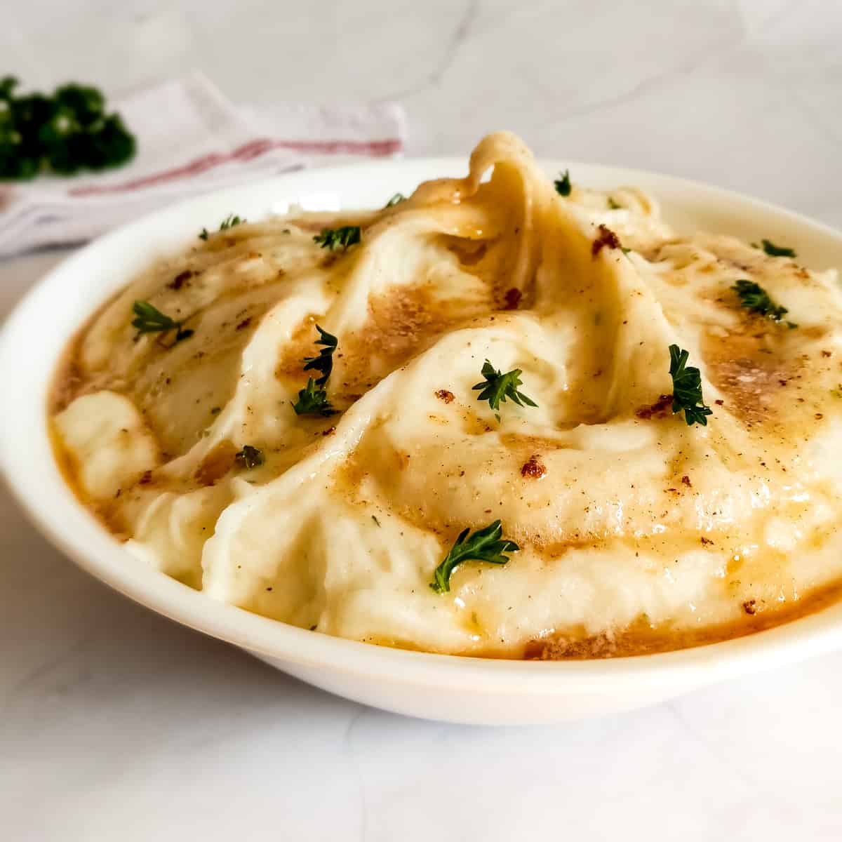 a bowl of creamy Amish mashed potatoes topped with brown butter and fresh parsley.