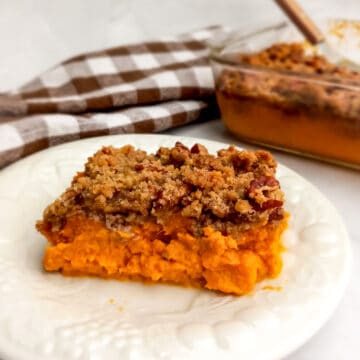 a serving of Amish sweet potato casserole on a plate and the 9" dish in the background.