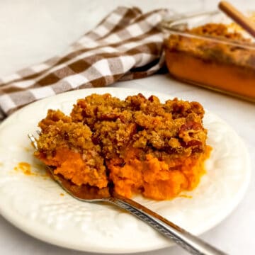 A fork is ready to dig into a plate of sweet potato casserole with streusel topping.