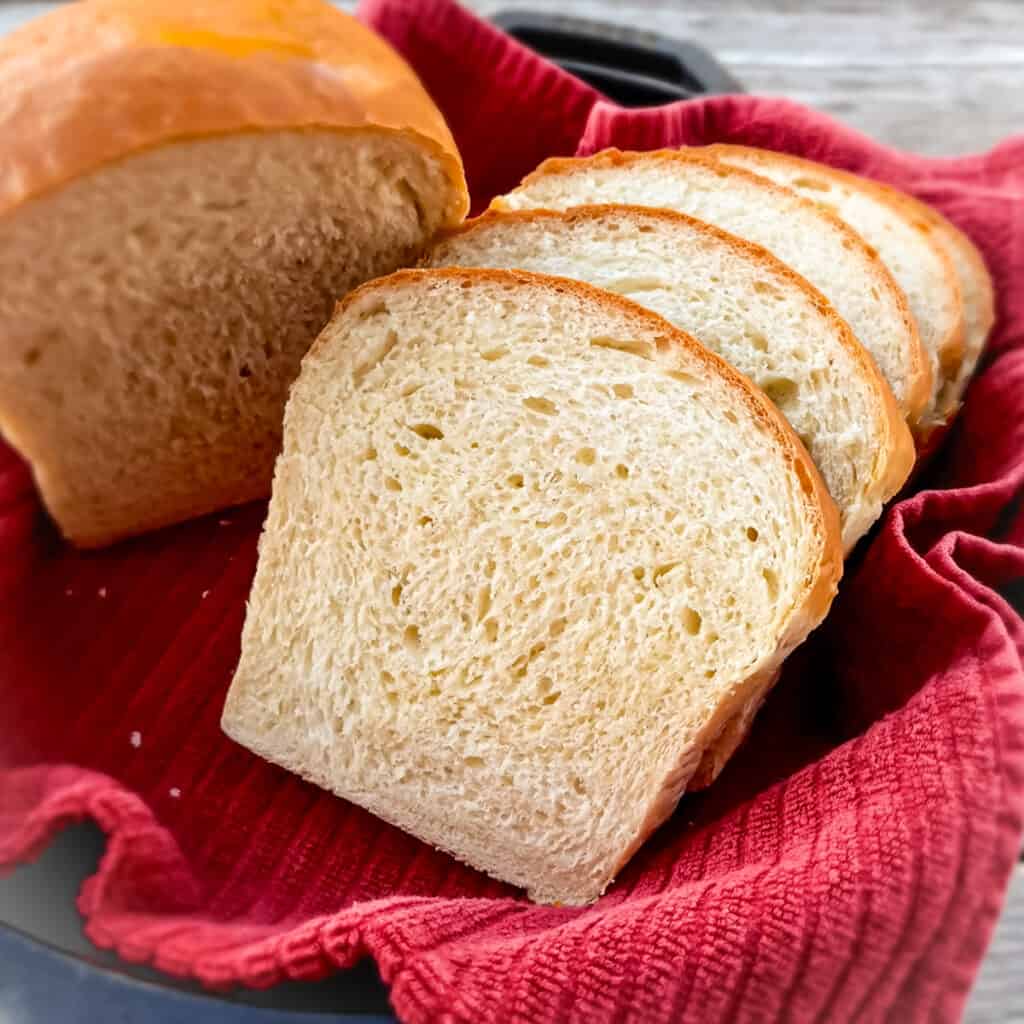 sliced homemade bread in a skillet with a red towel.