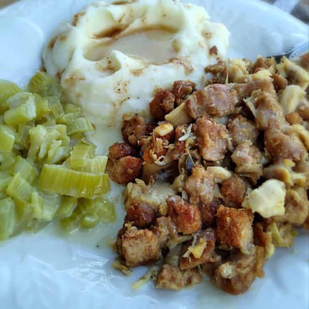 Amish wedding food on a plate: roasht, cooked celery, and mashed potatoes with gravy.