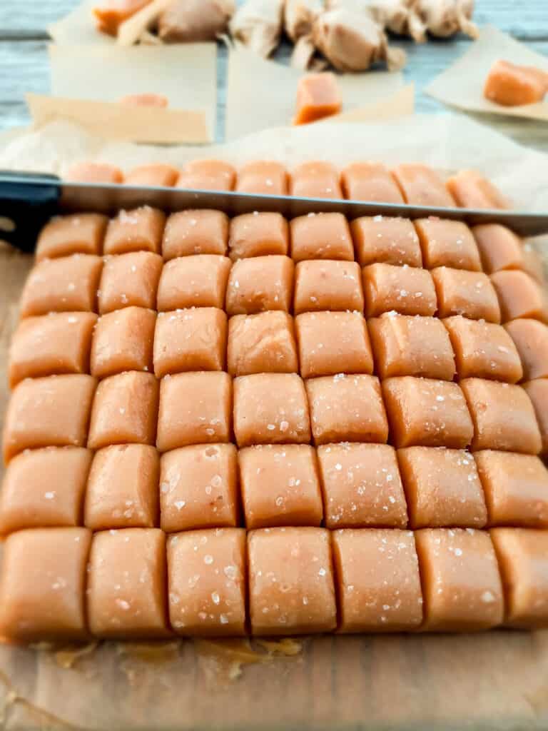 cut Amish caramels on a board and getting ready to wrap them in parchment papers.
