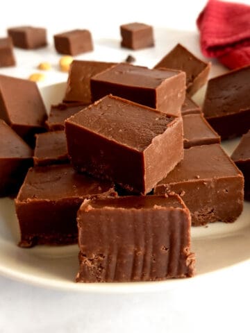 Amish peanut butter chocolate fudge pieces on a plate and scattered around.