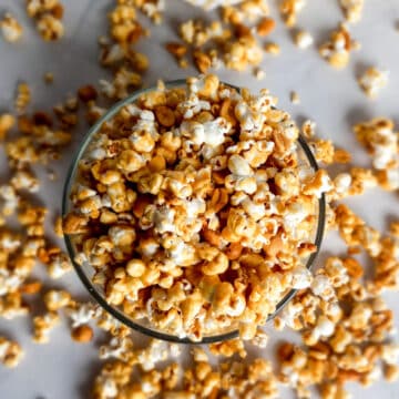 a bowl full of Amish caramel popcorn with pieces scattered around the bowl.