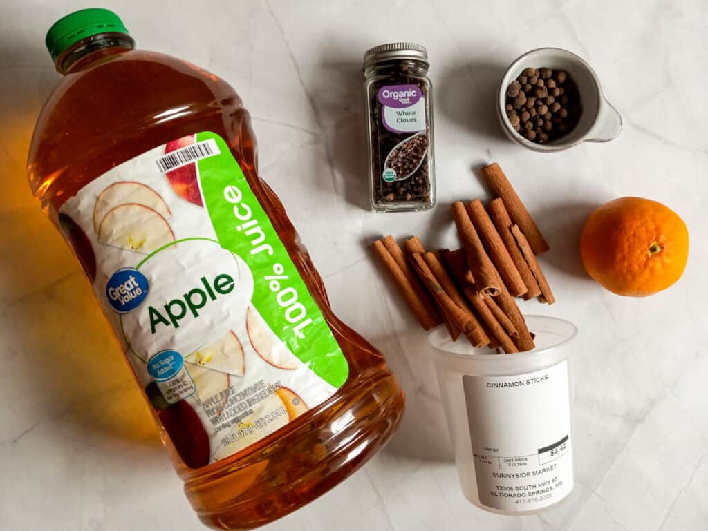 Ingredients: apple juice, cinnamon sticks, whole cloves, allspice berries, and an orange.